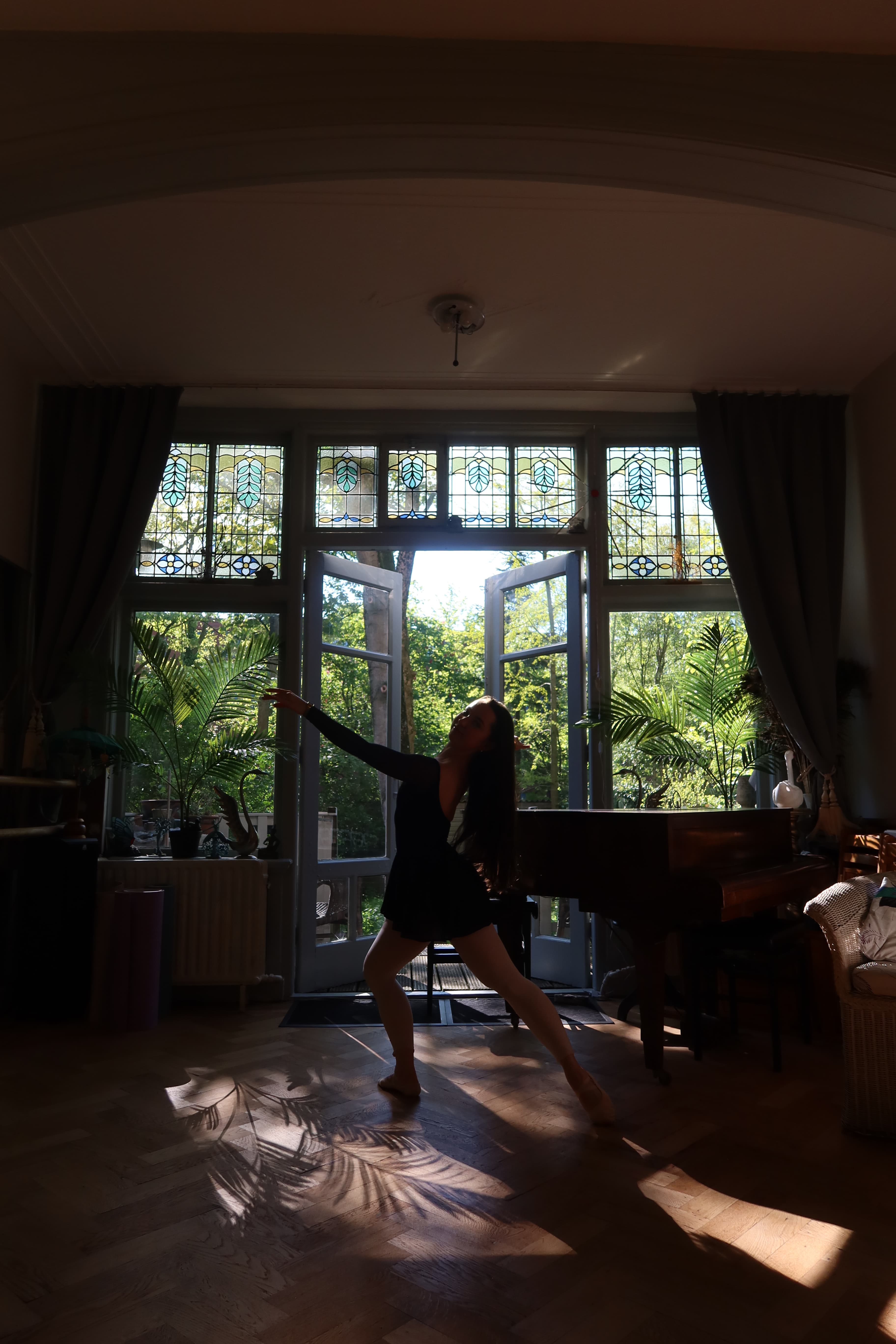 Ballet dancer silhouetted against studio windows