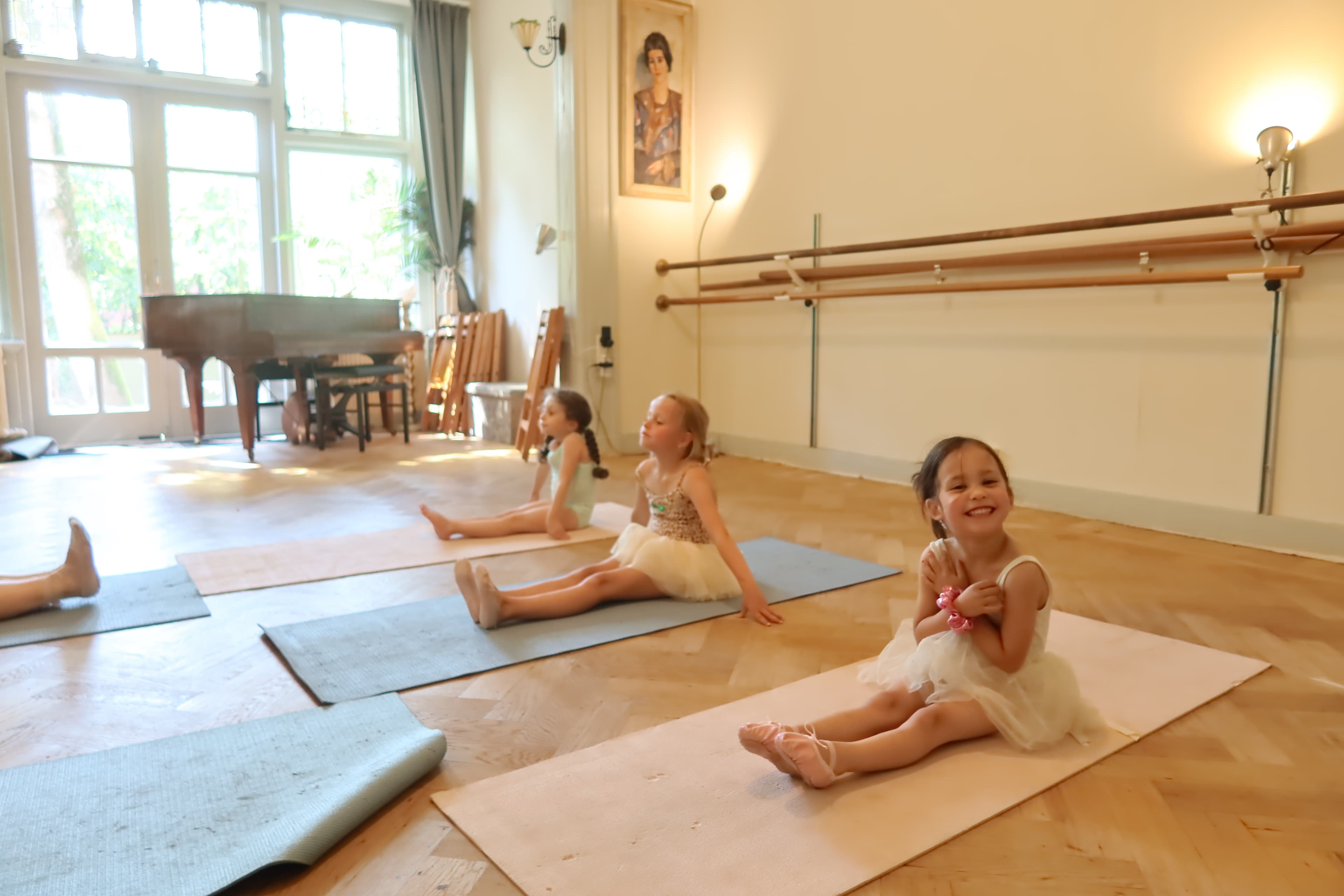 Young ballerinas doing floor exercises while smiling at the camera
